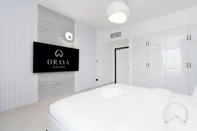 a white bedroom with a tv on a wall at Upgraded 2BR In La Riviera Marina - Close to Beach in Dubai