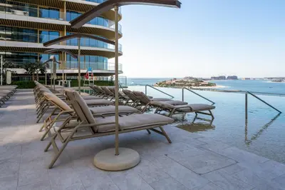 a row of lounge chairs sitting next to a building at Beach View 1BR at Beachfront 50 Off Eid Offer in Dubai
