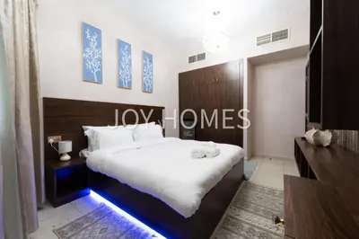 a bedroom with a large bed with white sheets at Amiralty Easy Stay in Dubai