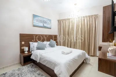 a bedroom with a bed with white sheets and blue pillows at Amiralty Easy Stay in Dubai