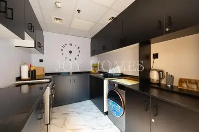 a kitchen with black cabinets and a washing machine in it at Amiralty Easy Stay in Dubai