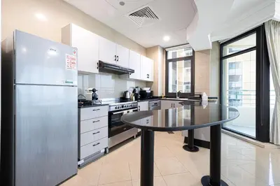 a kitchen with a stainless steel refrigerator and a table at Prime Location - 2BR with Spectacular Sea View in Dubai