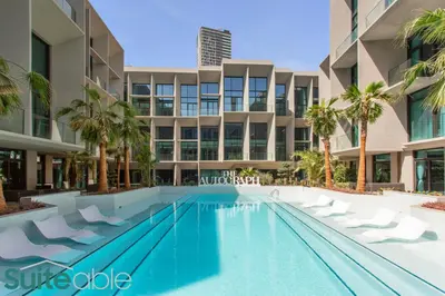 a swimming pool in front of a building with palm trees at Studio in The Autograph JVC w amazing facilities in Dubai