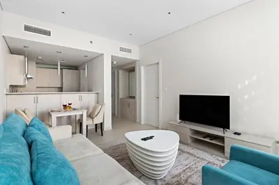 a living room with a blue couch and a tv at 1BR Apartment on The Palm Walk to Beach Mall Pool Restaurants in Dubai