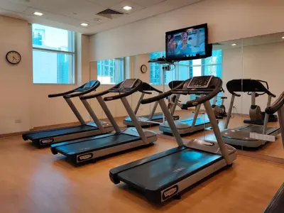 a gym with several tread machines and a flat screen tv at Luxury Two Bedroom Apt Facing Burj Khalifa in Dubai