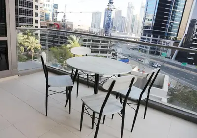 a table and chairs on a balcony with a view of a city at Luxury Two Bedroom Apt Facing Burj Khalifa in Dubai