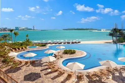 a resort pool with chairs and umbrellas and the ocean at Burj Alarab & Atlantis Palm Sea view, Beachfront, peaceful 3 Bedroom Apartment TIARA Residence with Pool, fast Wifi in Dubai