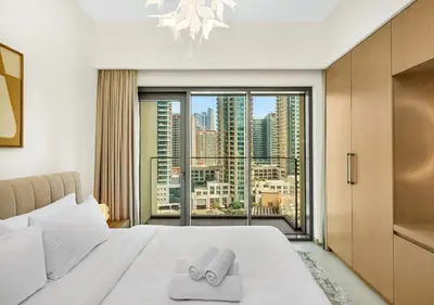 a bedroom with a white bed with a large window at Burj Royale 1 BR 5 Min Walk to Burj Khalifa in Dubai