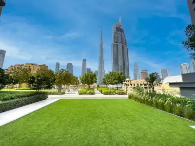 a park with a green lawn in front of a city at Burj Royale 1 BR 5 Min Walk to Burj Khalifa in Dubai