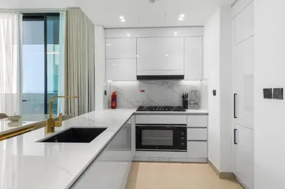 a white kitchen with a sink and a stove at Your Own Pool Spacious 2BDR Apartment JVC in Dubai