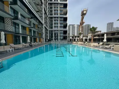 a large swimming pool with blue water in a building at Your Own Pool Spacious 2BDR Apartment JVC in Dubai