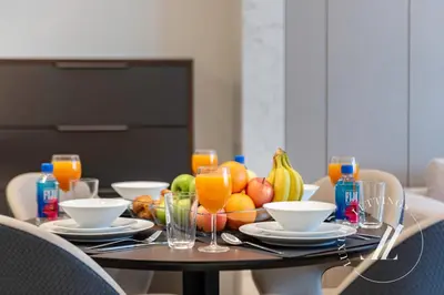 a table with a bowl of fruit and glasses of orange juice at 3BDR Business Bay Bliss High Floor Private Balcony in Dubai