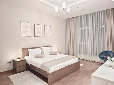 a white bedroom with a bed and a blue chair at The Palm Panorama Chic Apartment with Open Sea Views Managed by SunnyHomes in Dubai