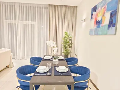 a dining room with a table and blue chairs at The Palm Panorama Chic Apartment with Open Sea Views Managed by SunnyHomes in Dubai