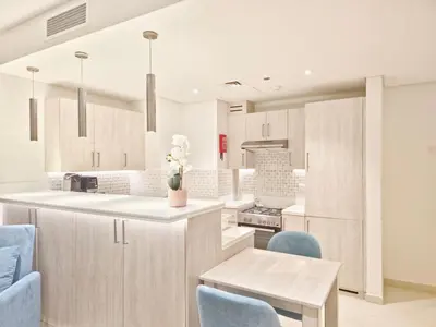 a kitchen with white cabinets and blue chairs at The Palm Hideaway Chic Apartment with Rooftop Vibes Managed by SunnyHomes in Dubai