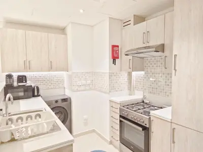 a kitchen with white cabinets and a stove top oven at The Palm Hideaway Chic Apartment with Rooftop Vibes Managed by SunnyHomes in Dubai