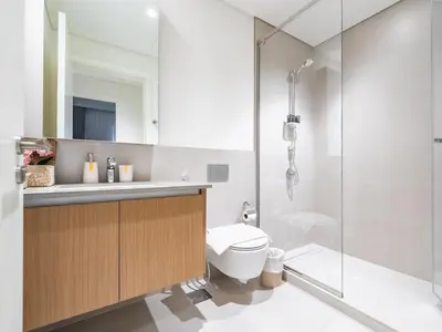 a bathroom with a toilet and a glass shower at Enjoy Sunset at Creek Beach in Dubai