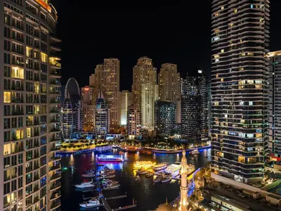 a view of a city at night with boats in the water at Cozy Home w Spectacular Water View in Dubai