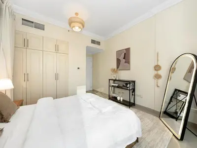 a bedroom with a large white bed and a mirror at Cozy Home w Spectacular Water View in Dubai