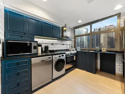 a kitchen with blue cabinets and a washer and dryer at Luxurious 2BR Apt with Marina View & Private Jacuzzi in Dubai
