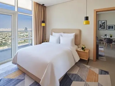 a bedroom with a large white bed and a large window at Private Apartment in Novotel JVT Comfort for 4 Guests in Dubai