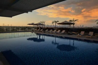 a man is standing next to a swimming pool at Private Apartment in Novotel JVT Comfort for 4 Guests in Dubai