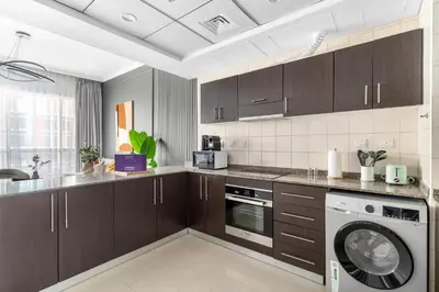 a kitchen with brown cabinets and a washer at Silkhaus Dubai Marina 1BR in Bay Central West Tower in Dubai