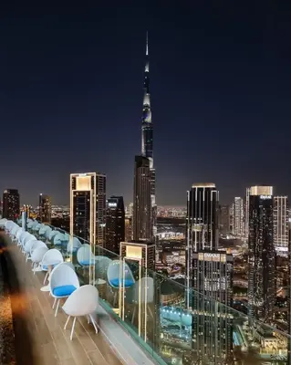 a view of a city skyline at night with tables and chairs at Sky Suite 1 Bedroom Apartment with Infinity Rooftop Pool and Dubais Ultimate Skyline View at Paramount Midtown in Dubai