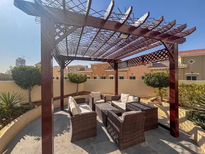a wooden pergola with a couch and chairs on a patio at Frank Porter - Rokane G22 in Dubai