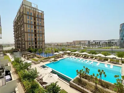 a large swimming pool with umbrellas and a building at Cosy 1 bed Apt in Dubai Hills in Dubai