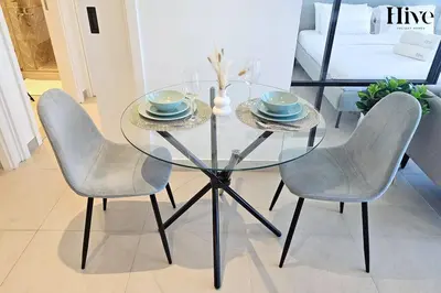 a glass table with two chairs and a bowl and plates at Cosy 1 bed Apt in Dubai Hills in Dubai