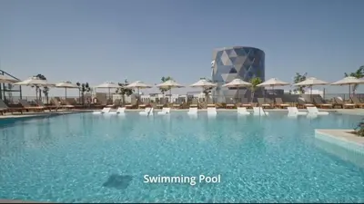 a swimming pool with chairs and umbrellas and a building at Cosy 1 bed Apt in Dubai Hills in Dubai