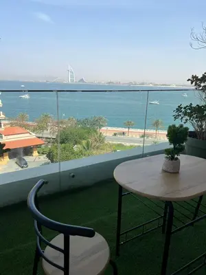 a table and chairs on a balcony with a view of the ocean at Cozy Home with Beach Access in Palm Jumeirah in Dubai