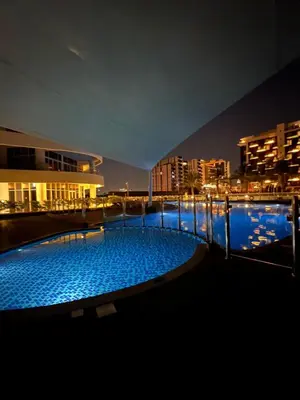 a large swimming pool at night with buildings at Cozy Home with Beach Access in Palm Jumeirah in Dubai