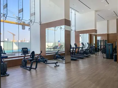 a gym with a lot of treadmills and ellipticals at Silkhaus Classic 1BDR Apartment in Binghatti House in Dubai