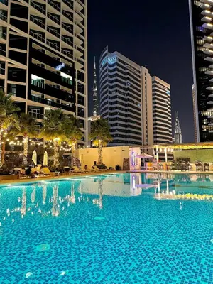 a large swimming pool in a city at night at Luxury Studio Apartment in Downtown Dubai in Dubai