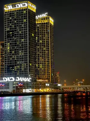 two tall buildings at night next to a body of water at Luxury Studio Apartment in Downtown Dubai in Dubai