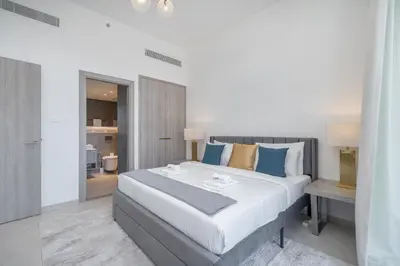 a bedroom with a large white bed with blue pillows at Luxury Stay JVC Modern 1BHK Pool & Gym Access in Dubai