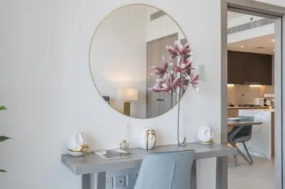a table with a vase of flowers and a mirror at Luxury Stay JVC Modern 1BHK Pool & Gym Access in Dubai