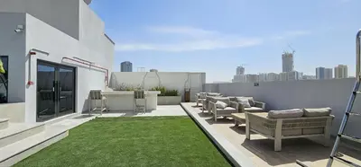 a rooftop patio with chairs and grass on a building at Luxury Stay JVC Modern 1BHK Pool & Gym Access in Dubai