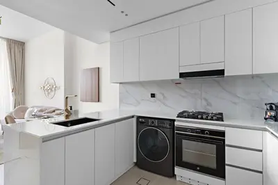 a kitchen with white cabinets and a dishwasher at FIRST CLASS 1BR Cozy Urban Getaway in Dubai