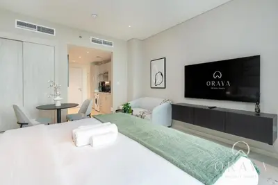a white bedroom with a large bed with a flat screen tv at Luxurious Studio In Seven Palm - Direct Beach Access in Dubai
