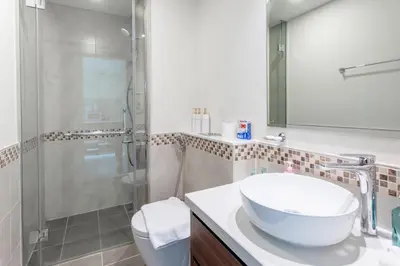 a white bathroom with a sink and a shower at Full burj khalifa view 1bhk app in Dubai