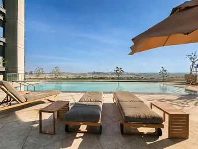 a swimming pool with two lounge chairs and an umbrella at Spacious & Elegant 1BD, for 2 in Nobles tower in Dubai