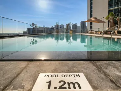 a swimming pool with a pool depth limit sign on a building at Spacious & Elegant 1BD, for 2 in Nobles tower in Dubai
