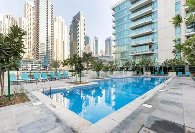 a swimming pool in the middle of a city with tall buildings at Serene 2BR Escape - Al Majara - Waterfront Stay in Dubai