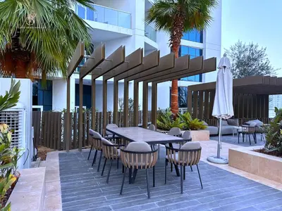 a patio with a table and chairs and a umbrella at Bellaviu Holiday Homes- Escape the Buzz-Your Quiet Spot in DAMAC Prive in Dubai