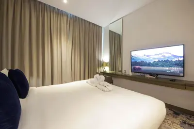 a hotel room with a white bed and a flat screen tv at Stylish Studio Apartment with pool in Business Bay in Dubai
