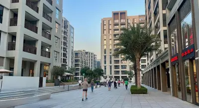 people walking down a sidewalk in a city with buildings at Sunset Creek Harbour, Dubai in Dubai