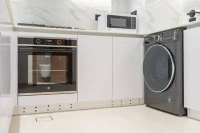 a kitchen with a washing machine and a microwave at Stylish 1BHK by CzechIn Pool & Gym Prime JVC in Dubai